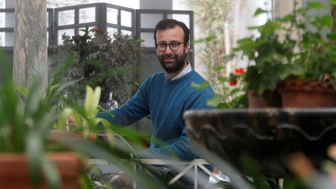 Manuel Fragero glimlacht, omringd door planten in Alberca ApartaSuites, een locatie in Córdoba beheerd door hem en ondersteund door Redforts software.